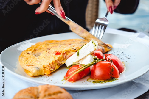 Woman eating scrambled eggs and cheese in restaurant