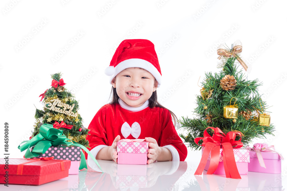 Little asian girl sitting on the floor with Christmas tree and gift boxes over white background