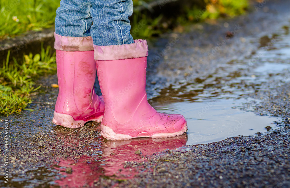 Little girl with pink wellys in the puddle