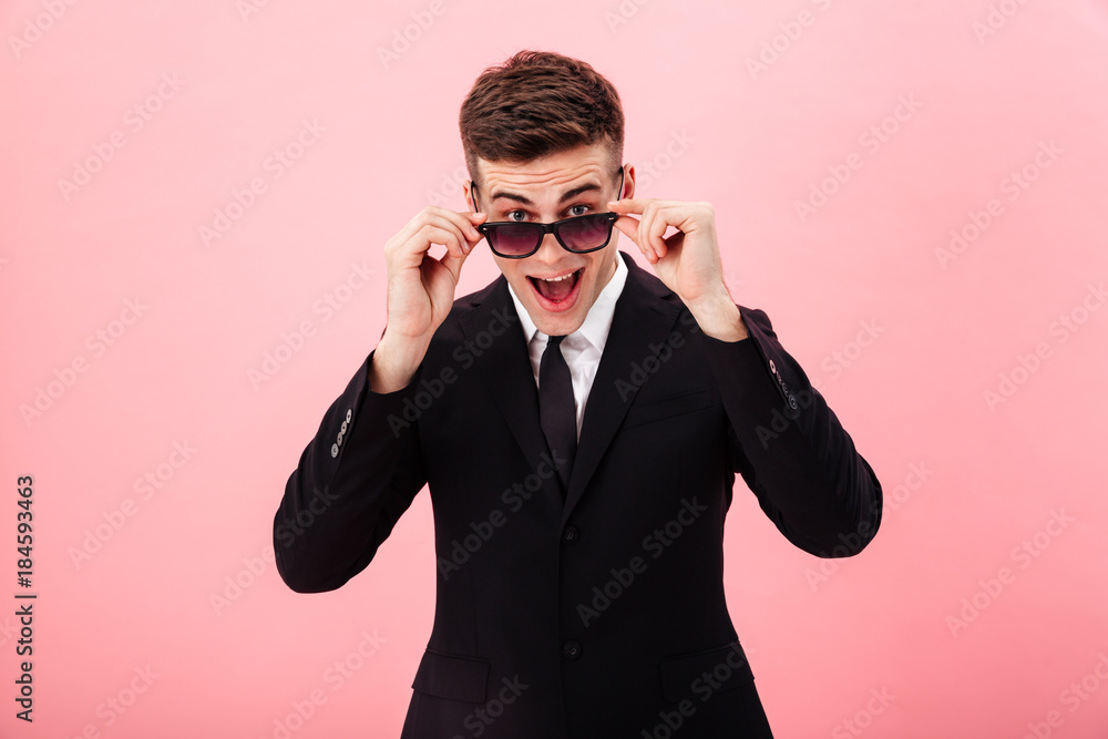 Confident man looking camera through sunglasses and smiling Confident man looking camera through sunglasses and smiling