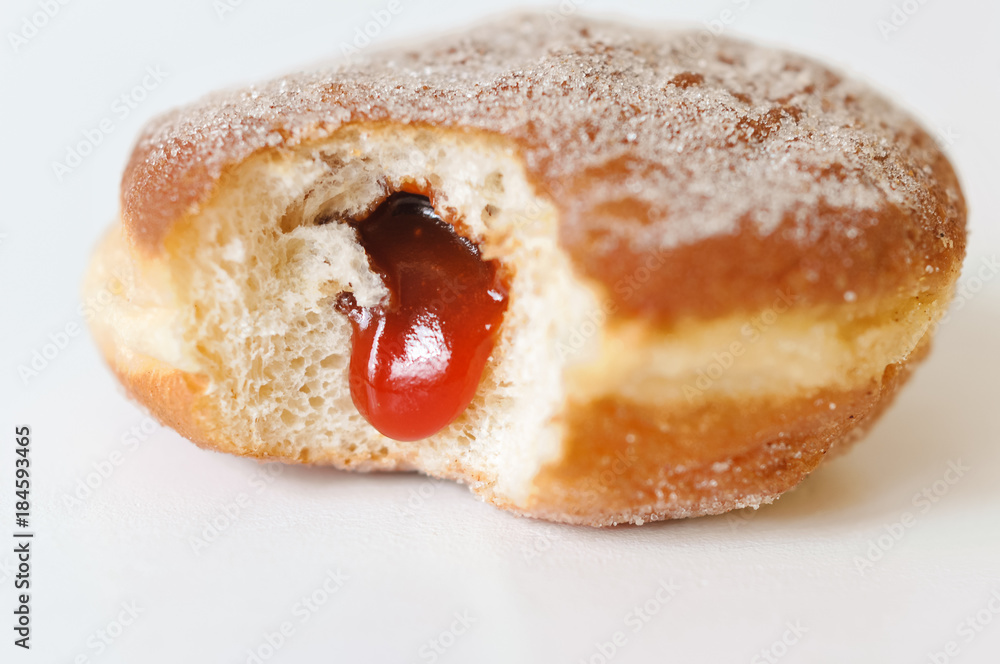German fried donut, so called Krapfen, Berliner or Pfannkuchen, filled with rose hip jam and dusted with cinnamon sugar, traditionally eaten at carnival and at New Year's Eve on white background - obrazy, fototapety, plakaty 