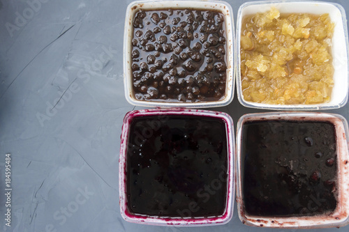 Four different types of jam on a gray background.