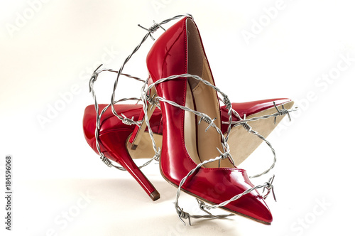 Uncomfortable shoes, sexism in fashion and foot pain concept with high heel stilettos wrapped in barbed wire representing the aches and pains caused to your feet by poorly constructed footwear