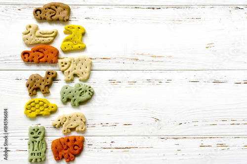 Delicious chewing colored bones and zoological biscuits  for dogs with different tastes on white wooden background