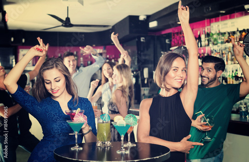 Women are drinking cocktails and having fun in nightclub.