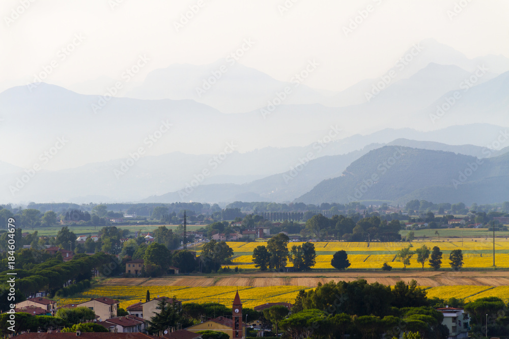Idyllic and scenic landscape of the city periphery - town outskirts, fields, forest, hills and mountains in the distance - Pisa, Tuscany, Italy; tourism, travel, vacation; background, copy space.
