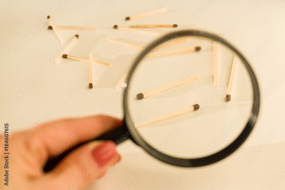 Fototapeta premium Match sticks with brown heads in a row. Matches under magnifier, white background.