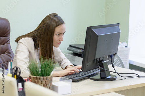 Young business woman working hard over the Desk in the study, economist accountant financial reporting, verifies accuracy of documents. Severe mental work