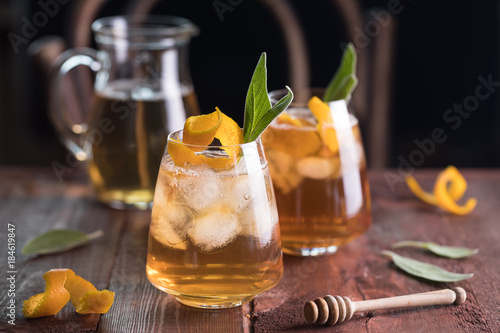 Refreshing iced tea with whiskey, honey, citron and sage on rustic wooden background. Selected focus photo