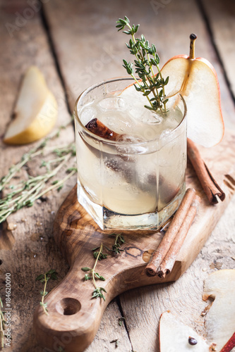 Cold pear white tea with thyme, cinna mon and honey on the olive desk and wooden background photo