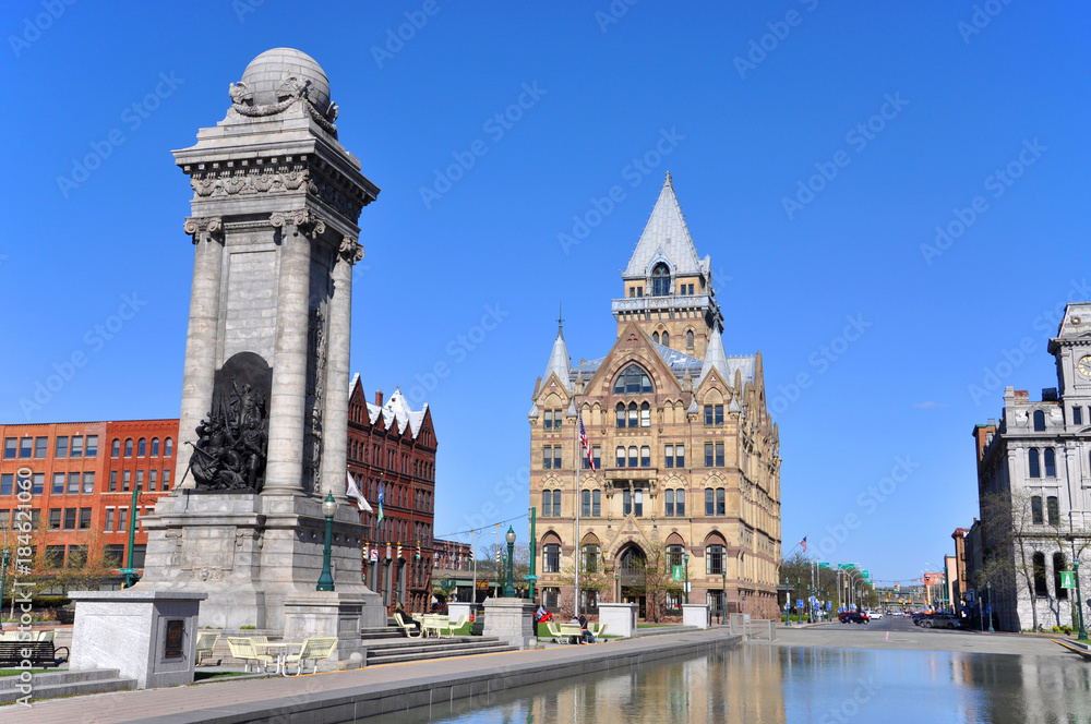 Soldiers' and Sailors' Monument and Syracuse Saving Bank Building at Clinton Square in downtown Syracuse, New York State, USA. Syracuse Savings Bank Building was built in 1876 with Gothic style.