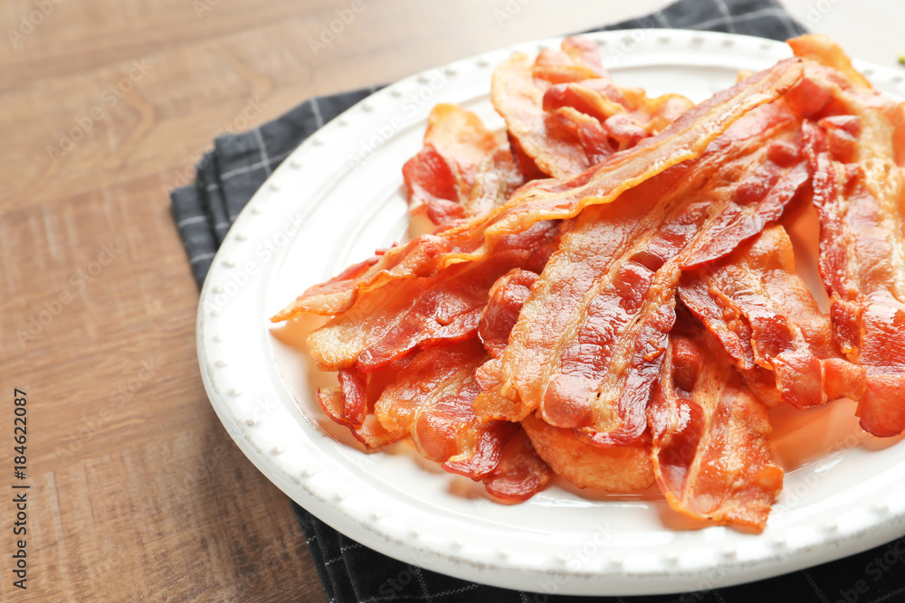 Plate with cooked bacon rashers on table Plate with cooked bacon rashers on table