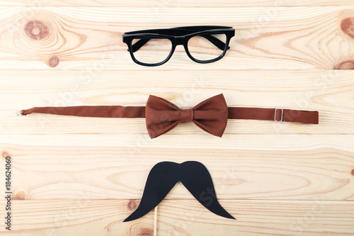 Bow tie with mustache and glasses on wooden table