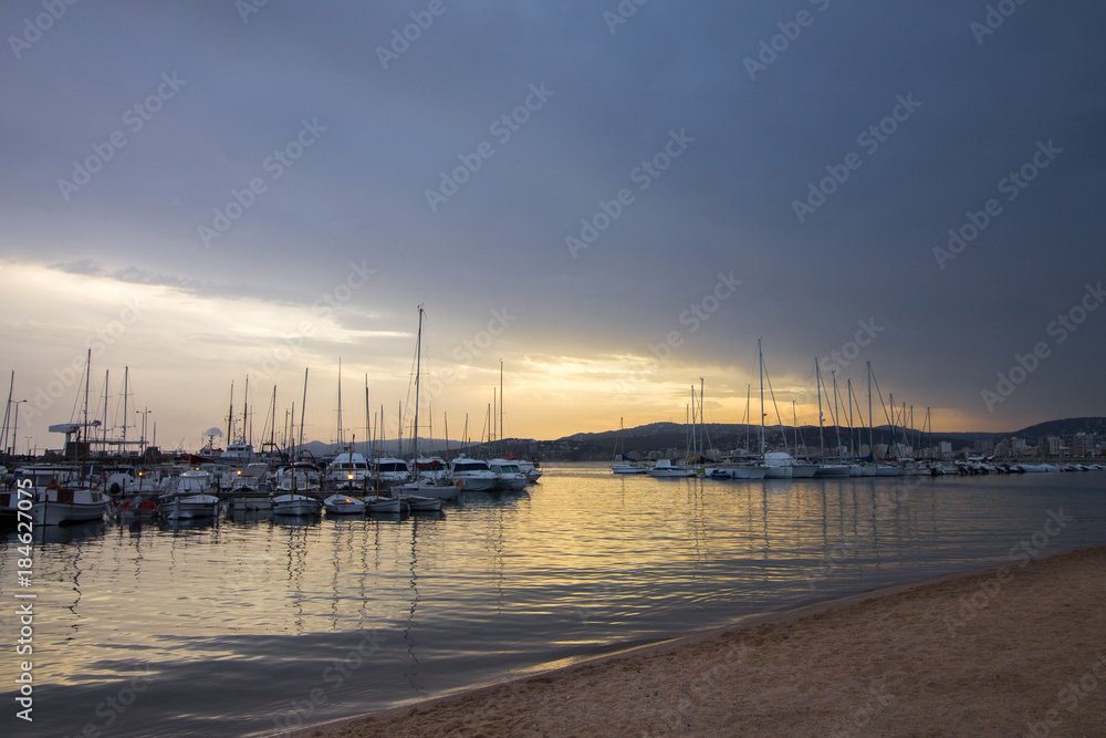 Numerous yachts in a Spanish port in the Costa Brava during sunset