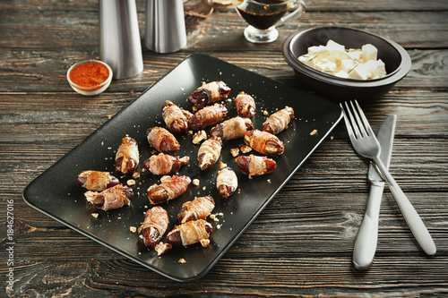 Plate with bacon wrapped dates on table photo