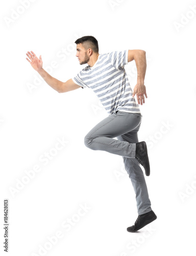Young man in casual clothes running against white background