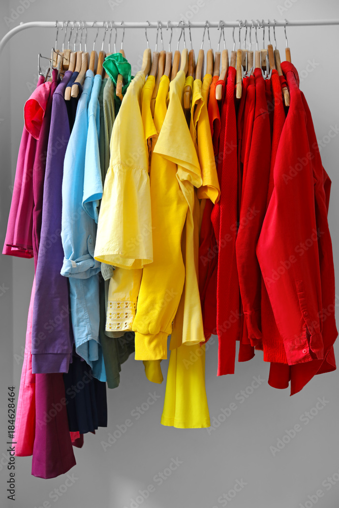 Rack with rainbow clothes on grey background Rack with rainbow clothes on grey background