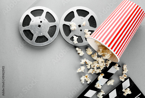 Composition with popcorn, movie clapper and cinema film on grey background
