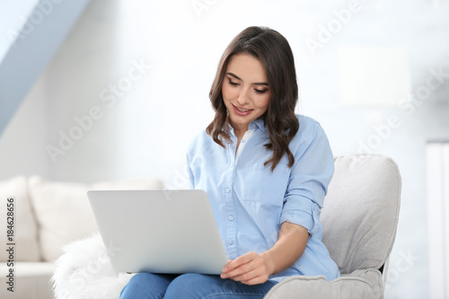 Young woman using laptop at...