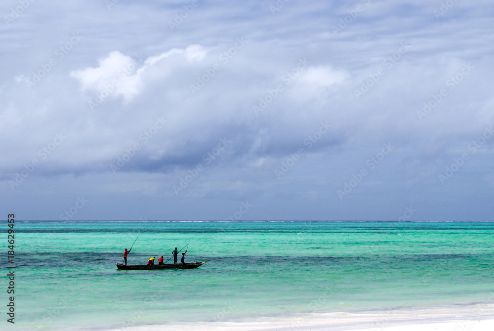 Unidentified fishermen paddling their boat along a shallow coral reef