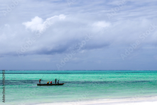 Unidentified fishermen paddling their boat along a shallow coral reef © Nieuwenkampr