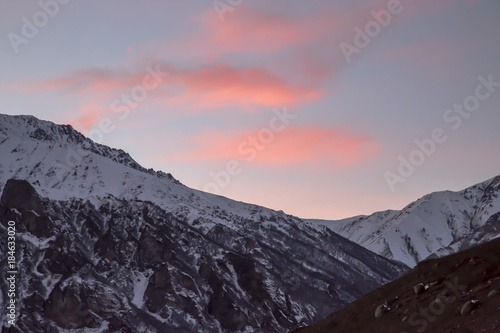 Вечерний пейзаж, оранжевые облака в небе над снежными горными склонами, природа Северного Кавказа