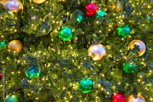 Red and green holiday ornaments on a Christmas tree