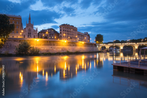 Tiber riverside with Church of the Sacred Heart of Jesus in Prati and mirror reflection during evening blue hour in Rome, Italy