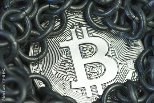 Shiny Bitcoin coin surround by metal chains, Bitcoin is a cryptocurrency using the blockchains technology