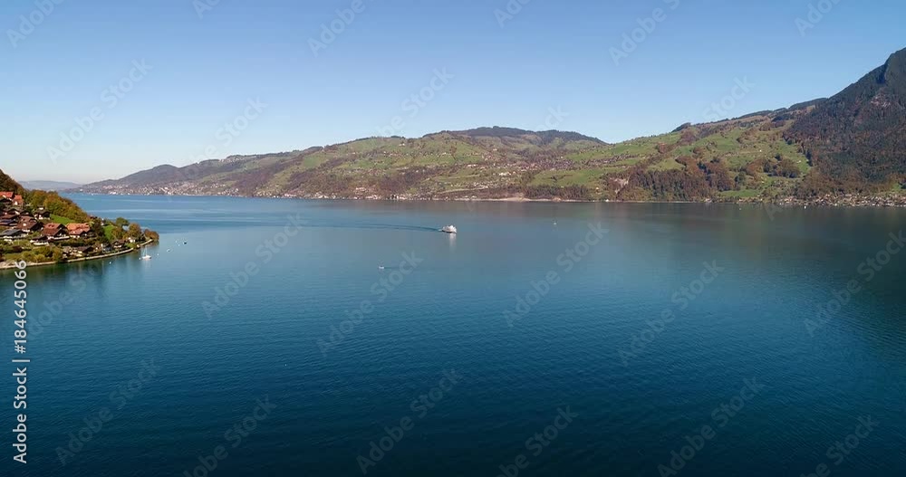 Yacht on a lake, Cinema 4k aerial view over a turquoise sea, the thunersee and over a large tourist ship, on a sunny fall day, near spiez, in berner oberland, in the alps of switzerland Yacht on a lake, Cinema 4k aerial view over a turquoise sea, the thunersee and over a large tourist ship, on a sunny fall day, near spiez, in berner oberland, in the alps of switzerland