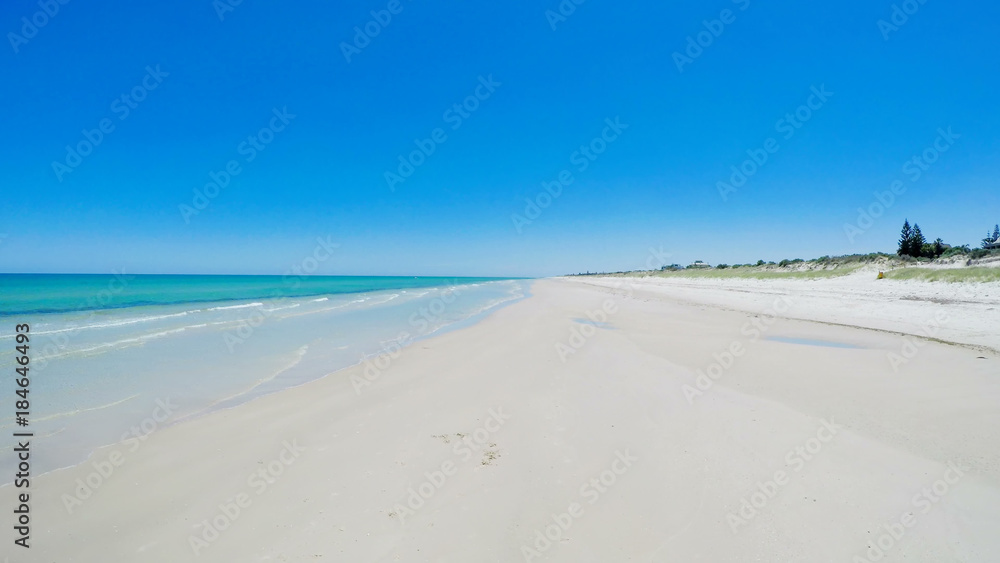 Drone aerial view of wide open white sandy beach, taken at Tennyson, South Australia with nearby luxury two story homes overlooking the coast.