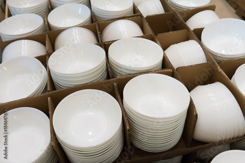 Stacks of white and round shaped porcelain bowls in corrugated boxes. Detail