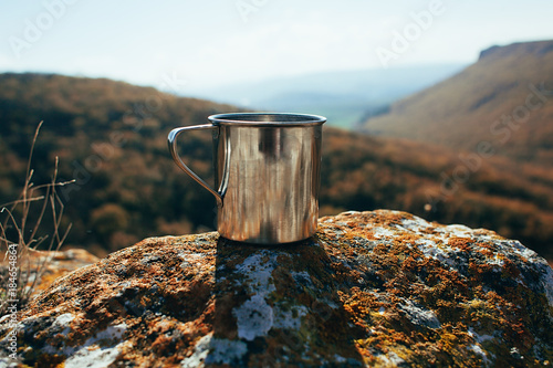 Metal cup on rock in mountain forest. Autumn colors, close up, copyspace. beautiful landscape