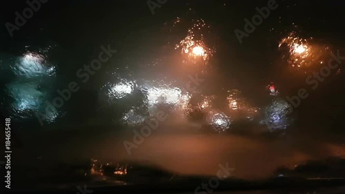 Defocused lights. Hard rain on windshield in the night.