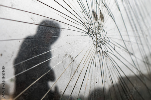 At the bus stop broken glass. There are a lot of cracks. On the background of the silhouette of a man.