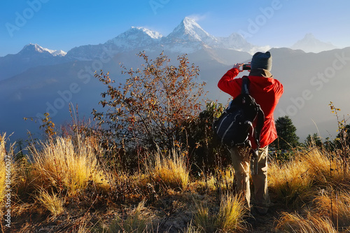 Tourist, a man, makes photo of Annapurna mountain with his mobile phone from Poon Hill, famous view point in Himalaya range at sunrise, Annapurna Circuit Trek, Annapurna Himal, Himalaya, Nepal, Asia photo