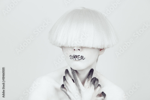 Fotografie A girl with white skin and a white wig with an inscription on her lips 'surreal'