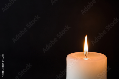 Candle with flame on the dark background. Condolence and religion concept. Empty place for a text.