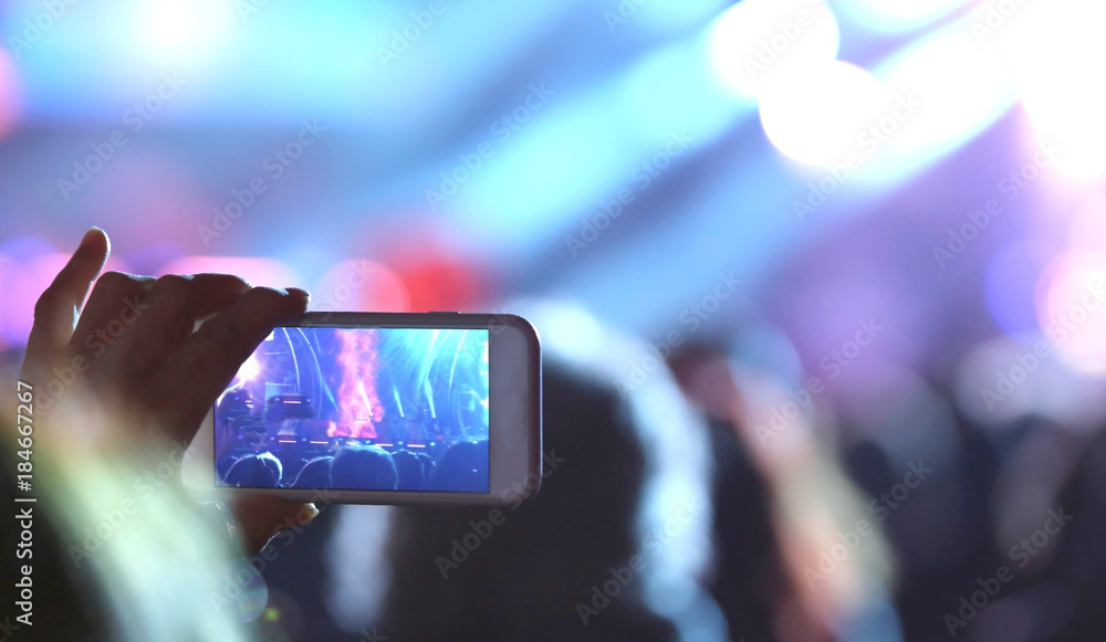 young girl takes a photo with the smartphone during the concert