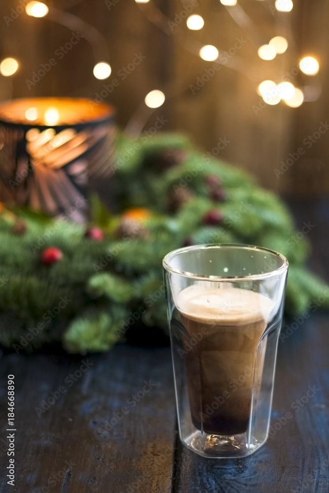 Coffee in a glass on a table and glowing Christmas tree on a dark background Coffee in a glass on a table and glowing Christmas tree on a dark background