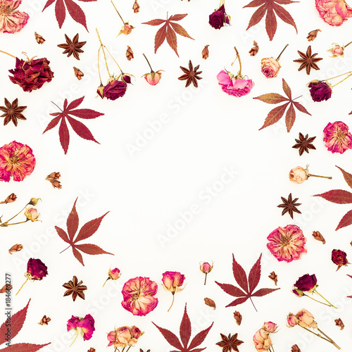 Floral frame of red leaves and dried roses on white background. Flat lay, top view.