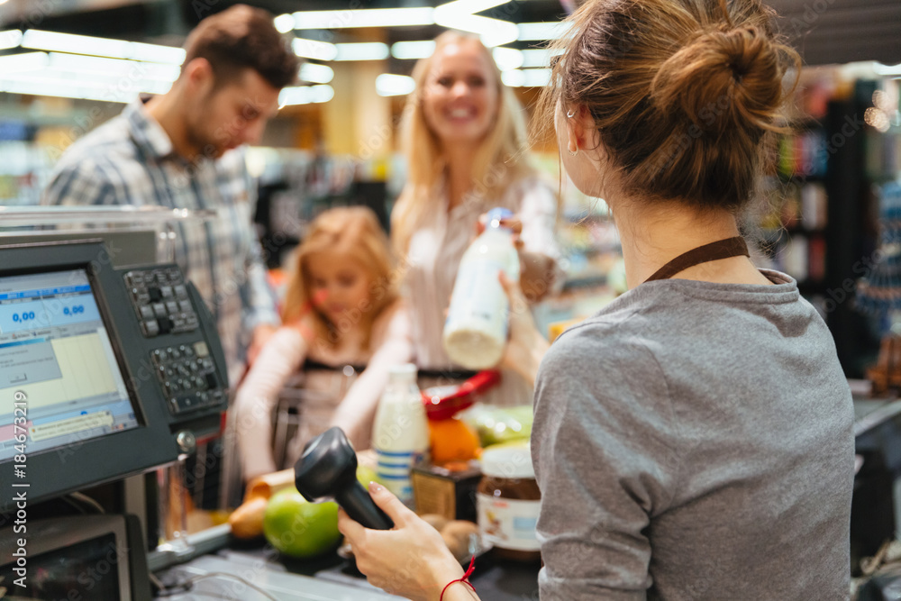 © Drobot Dean - Cheerful family standing at the cash counter