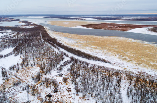 This is aerial view of the thick spruce forest with a big river in a cold winter day. © aapsky