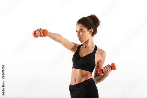 Serious fitness woman doing exercise with dumbbells and looking away
