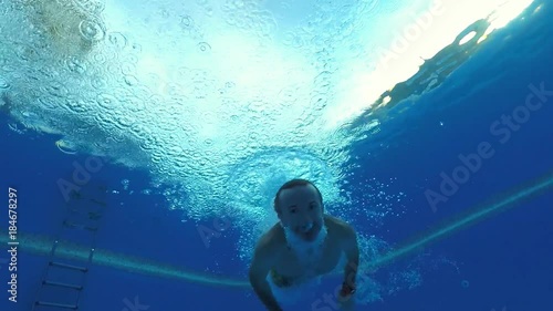 A man jumps into the pool and swims in front of the camera