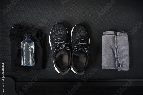 Top view of black tone fitness accessories on treadmill background , running concept