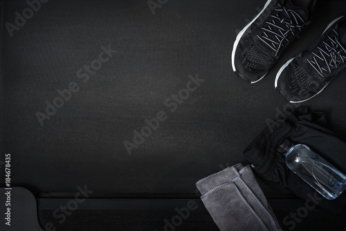 Top view of black tone fitness accessories  on treadmill background with copy space, running concept