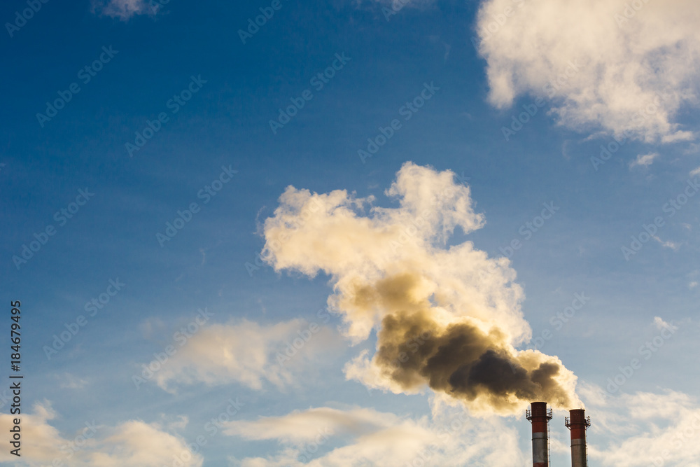 Stream of dark smoke from the chimney of factory in the industrial district