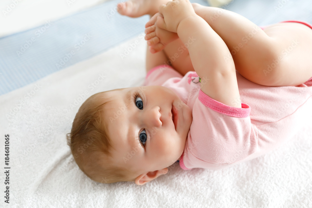 Cute baby taking feet in mouth. Adorable little baby girl sucking foot.