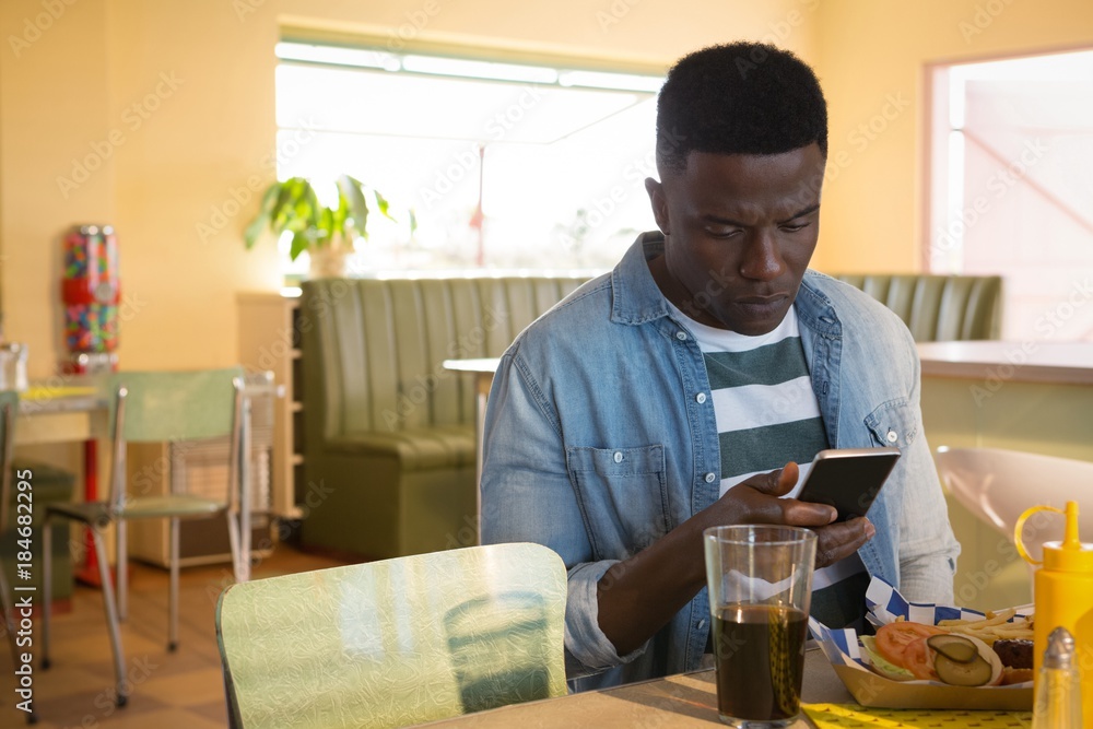 Young man using his mobile phone while having food Young man using his mobile phone while having food